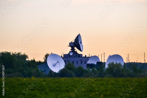 Several large satellite communications antennas in the field in the early morning. Space Communication Center