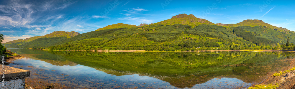 Panoramic day view of Loch Long, green mountains and bright blue sky in Scotland