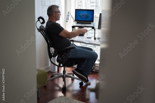Man preparing architectural design on laptop at home photo