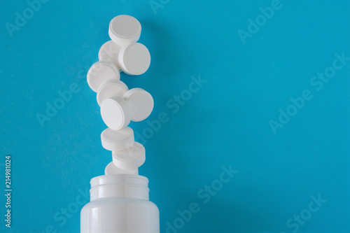 medicine tablets and medicine bottle isolated on blue background. Top view