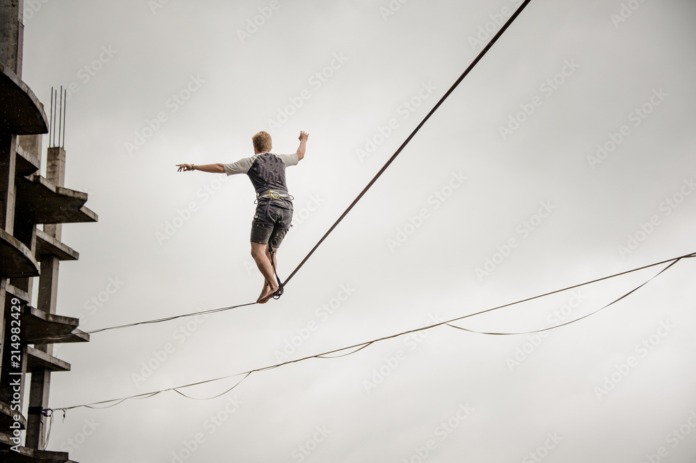 Young active man walking on the slackline rope