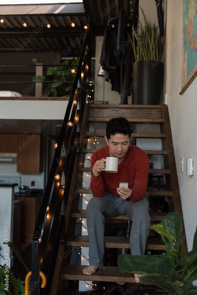 Man having coffee while using mobile phone on stairs Man having coffee while using mobile phone on stairs
