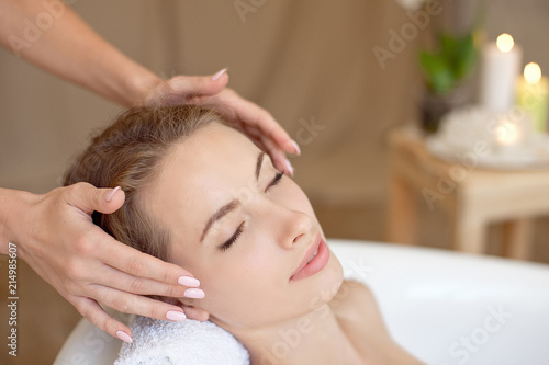Woman face with perfect skin doing facial massage in a bathtub.