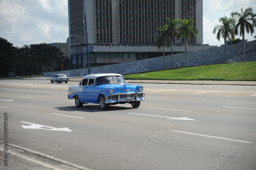 Brightly colored classic American cars serving as taxis pass on the main street in front of the Capitolio building in Central Havana  Cuba