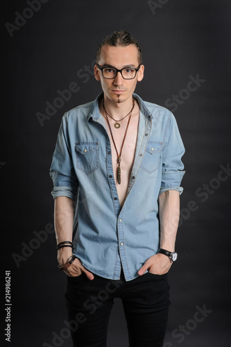 Young handsome boy in denim shirt and glases, curly hair, hands in pockets