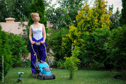 Gardener girl is cutting the grass with the mower photo