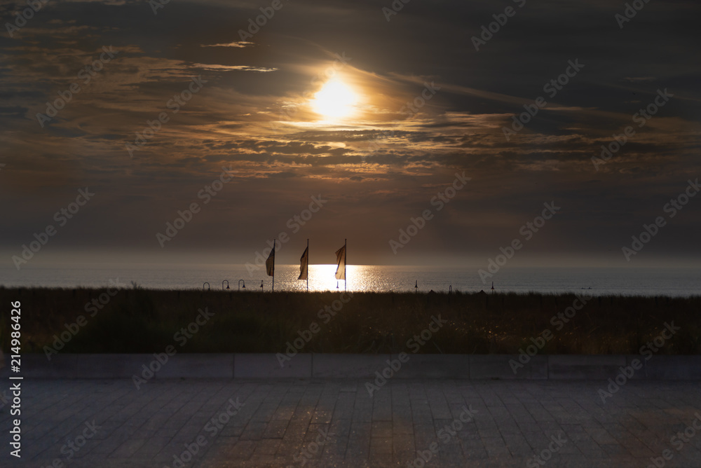 Silhouettes of flags at the sun set on the Katwijk beach, Netherlands