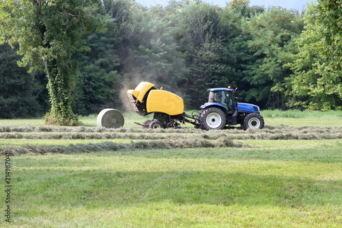 Foto trattore agricolo blu con macchina fienagione