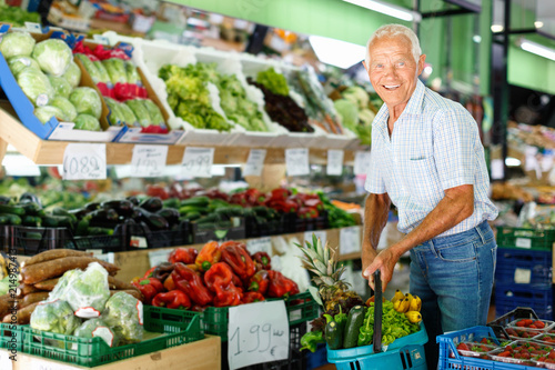 Satisfied elderly man with basket filled with fresh fruits and vegetables