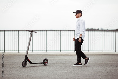 Photo of modern man with electric scooter at the street