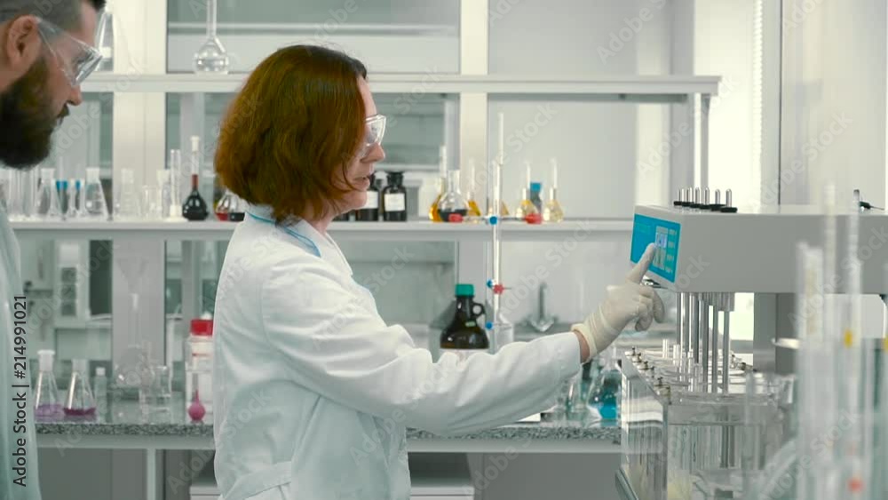 Woman chemist show laboratory assistant how to adjust the equipment Woman chemist show laboratory assistant how to adjust the equipment