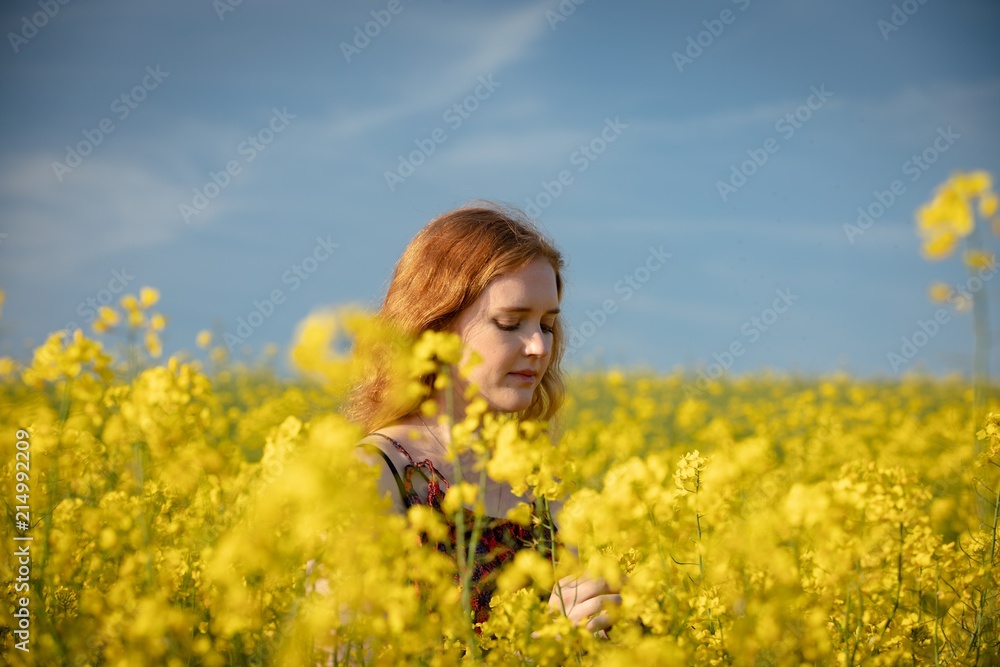 Woman touching crops in the mustard field on a sunny day