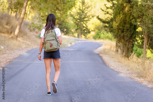 Woman hiker with backpack walking alone on roads in the forest ,concept of journey travel or sport background. © Inna