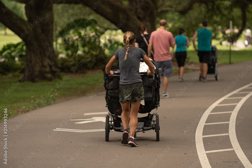 unknown woman stays very fit running with her stroller in the park