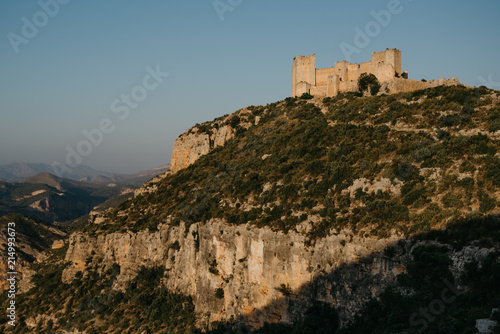 An ancient castle on the top of the hill above the valley in Spain on the sunset lights. El Castillo de Chirel. 