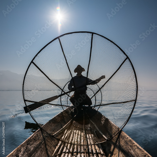 Burmese fisherman on bamboo boat catching fish in traditional way with handmade net. Inle lake  Myanmar  Burma  travel  destination
