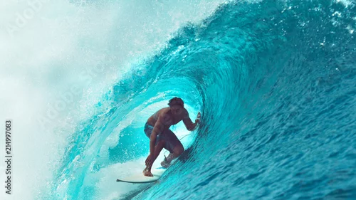Obraz ZBLIŻENIE: Wybitny sportowiec surfuje po dużej beczce fal oceanicznych lśniących w słońcu.