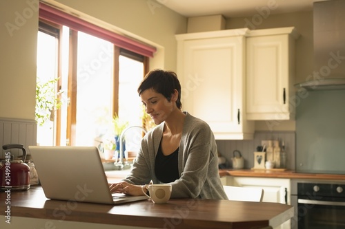 Woman using laptop in the kitchen photo