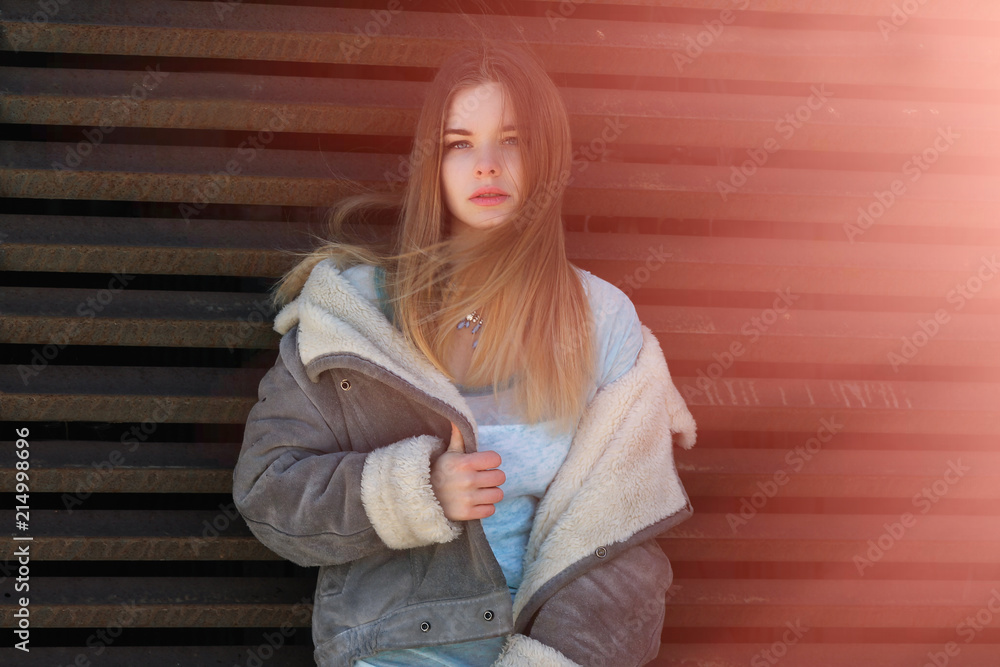 Blonde woman with her hair blowing in the wind. Young girl in stylish clothes Blonde woman with her hair blowing in the wind. Young girl in stylish clothes