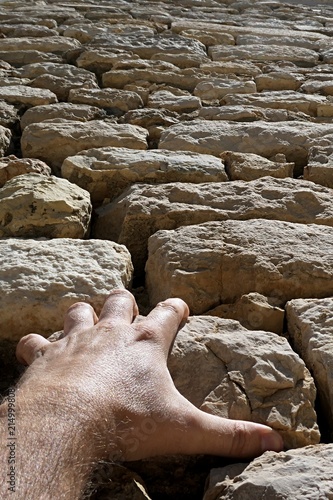 Hand of adult man holding stone on wall of roman church, trying to climb photo