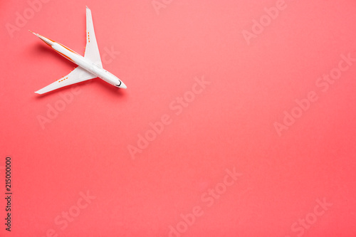 Top view of an airplane on trendy pink background. Bright summer color. Travel concept.