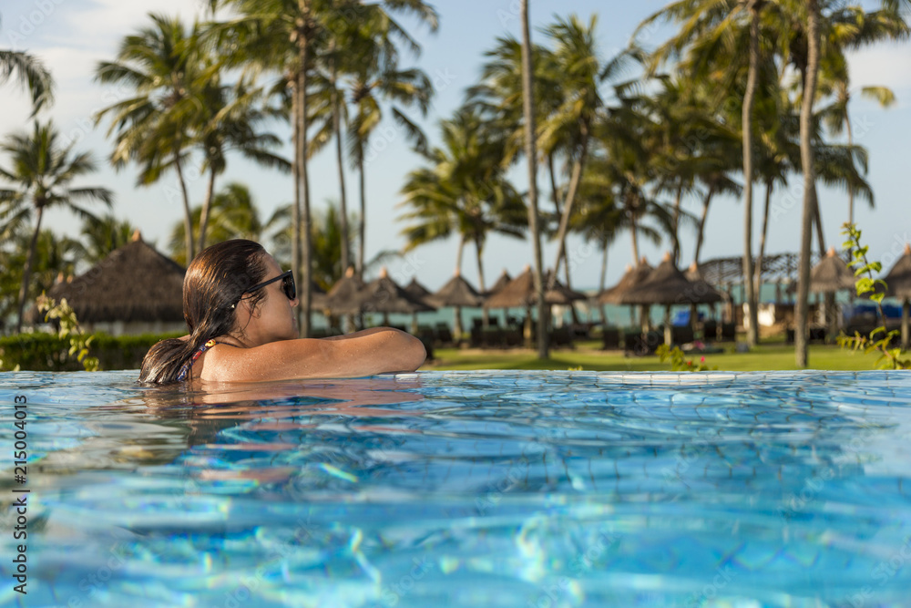 Beautiful brazilian woman enjoying vacation holidays at a pool.