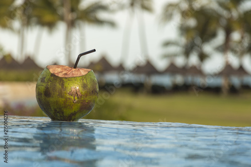 coconut on the edge of the tropical pool at sunset. photo