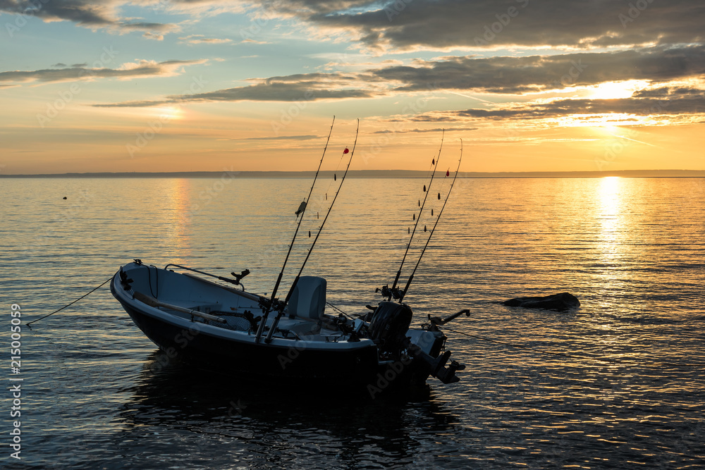 Naklejka premium Single trolling boat in lake sunset scenery