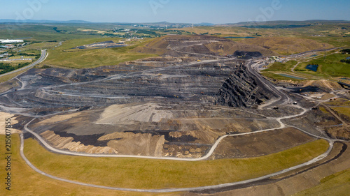 Aerial drone view of a huge opencast coal mine cut into a rural hilly area photo