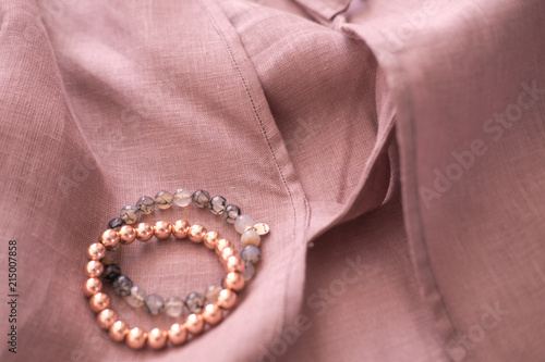 Rose gold gemstone bracelets and earrings on a soft blush linen fabric texture. Fashion and beauty blogging concept