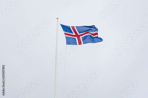 A civil flag and ensign Iceland against a clouded sky.