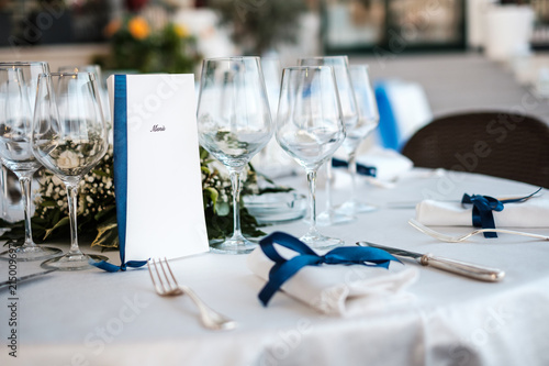 Tavola elegante di ristorante imbandita con menù, tovaglioli e posate per matrimonio e laurea photo