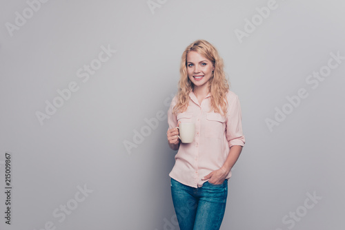 Bilde på lerret Charming girl in pink shirt holds in her hand white mug with drink and looks dir