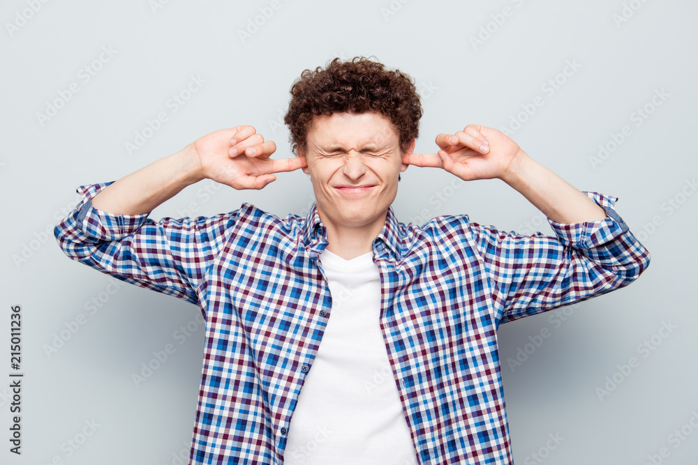 Silent and noise concept. Close up portrait of upset exhausted guy doesn't want to listen nothing isolated on light gray background Silent and noise concept. Close up portrait of upset exhausted guy doesn't want to listen nothing isolated on light gray background