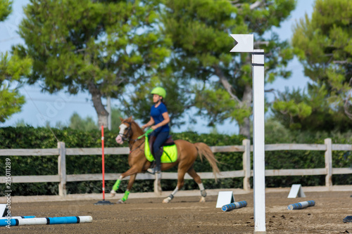 Close Up of the Red Flag of Start on Blur Man Riding a Horse in a Riding School during a Competition on Blur Background