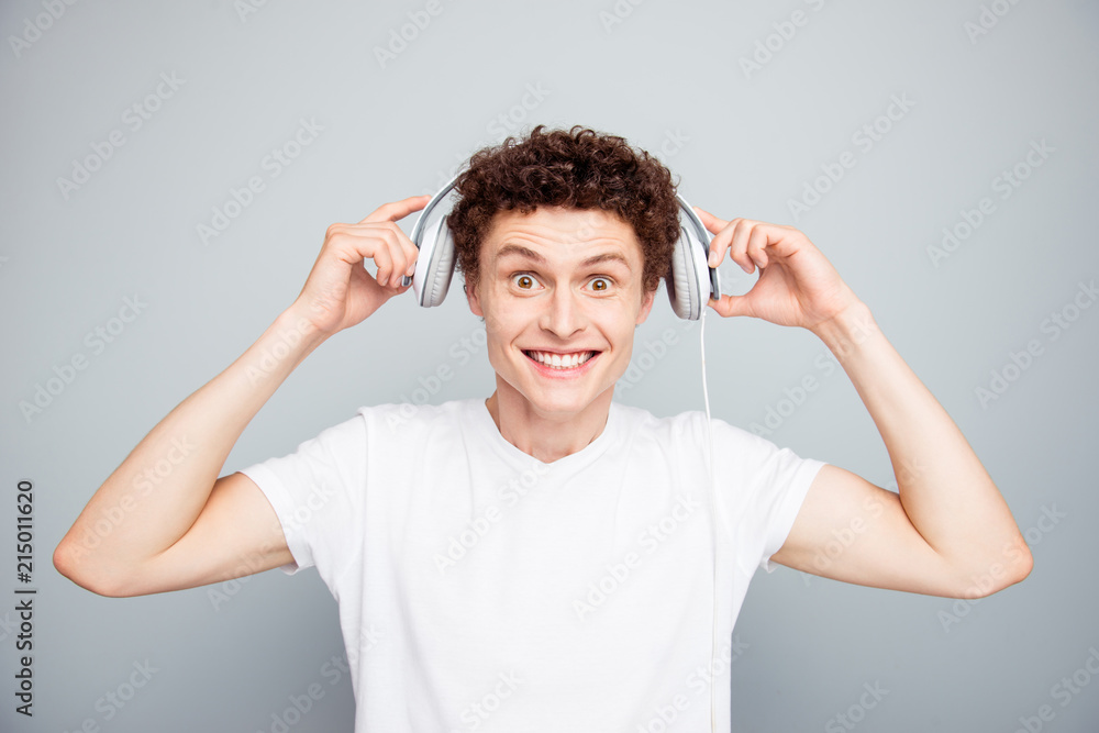Portrait of young handsome and attractive guy dresses white headphones on his head that you listen to good music isolated on light gray background Portrait of young handsome and attractive guy dresses white headphones on his head that you listen to good music isolated on light gray background