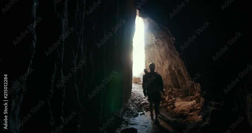 Young friends explorers in helmets leaves the dark cave Young friends explorers in helmets leaves the dark cave