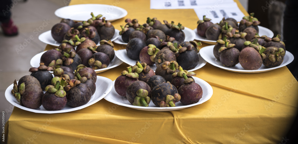 some mangosteens served in plates for the people to eat. some mangosteens served in plates for the people to eat.