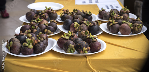 some mangosteens served in plates for the people to eat.