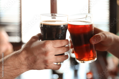 Friends clinking glasses with beer in pub