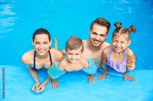 Young family with little children in swimming pool on sunny day