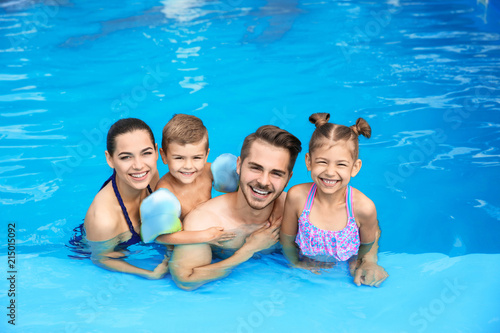 Young family with little children in swimming pool on sunny day