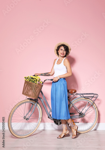 Fototapeta Naklejka Na Ścianę i Meble -  Portrait of beautiful young woman with bicycle near color wall
