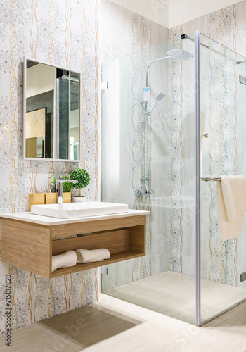 Spacious and bright modern bathroom interior with white walls, a shower cabin with glass wall, a toilet and faucet sink