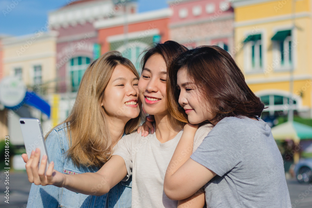 Attractive beautiful asian friends women using a smartphone. Happy young asian teenage at urban city while taking self portraits with her friends together with a smartphone. Attractive beautiful asian friends women using a smartphone. Happy young asian teenage at urban city while taking self portraits with her friends together with a smartphone.