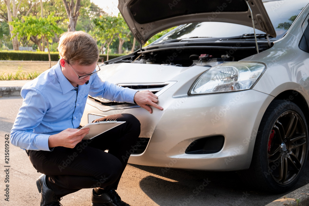 Insurance agent writing document on clipboard examining car after accident, Insurance concept Insurance agent writing document on clipboard examining car after accident, Insurance concept