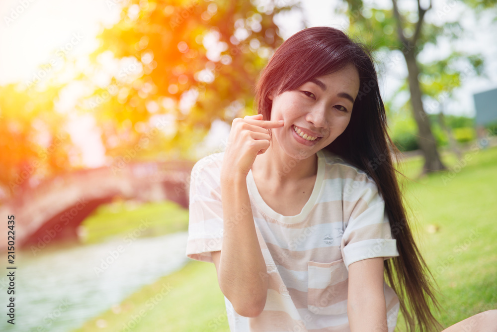 Cute asian woman smile with finger dimples cheek in the park Cute asian woman smile with finger dimples cheek in the park