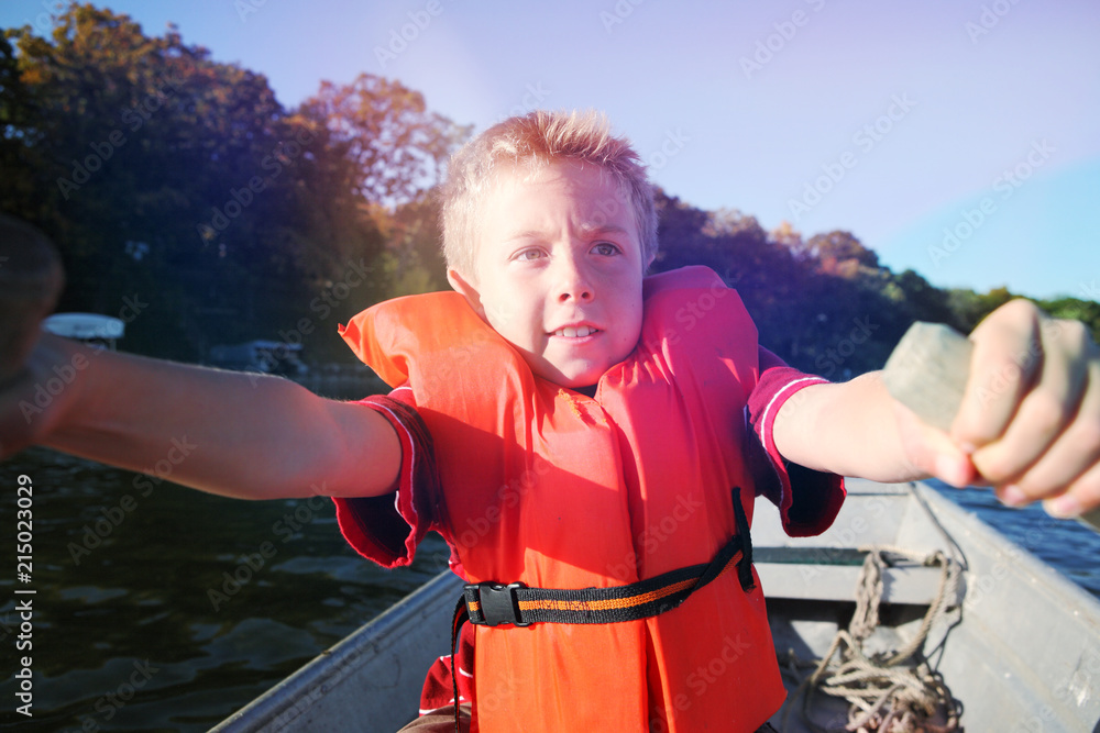 Fotografie Boy rowing a boat on a lake