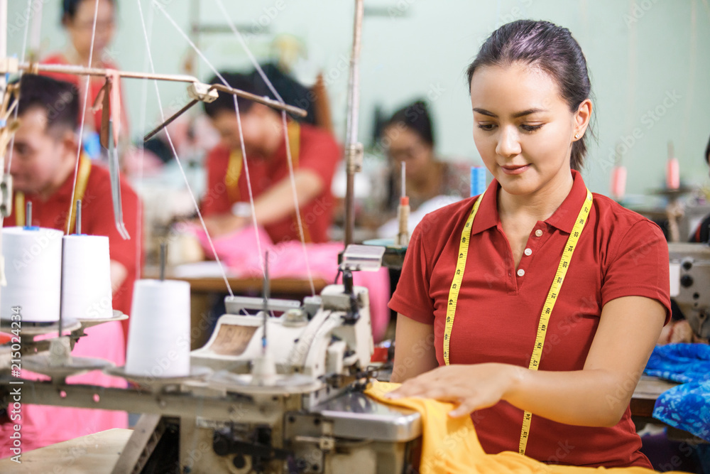 Fotografie Seamstress in textile factory sewing using industrial sewing mac