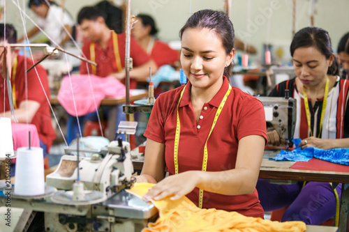 Obraz na plátne Seamstress in textile factory sewing with industrial sewing mach